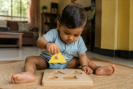 Indian toddler about one year old holding a knobbed yellow triangle piece above a wooden shape puzzle board on a floor mat