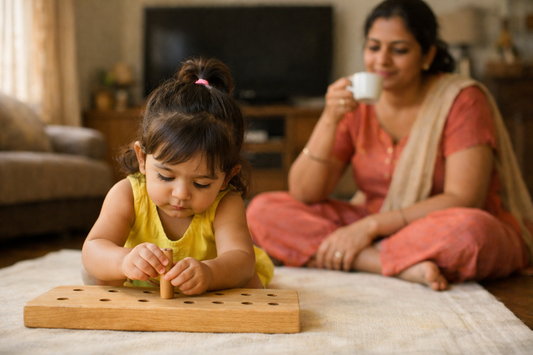 2 year old Indian toddler playing on the floor with a wooden posting toy while the television behind her is switched off
