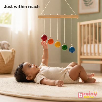 Baby playing with a colorful mobile toy in a nursery setting.