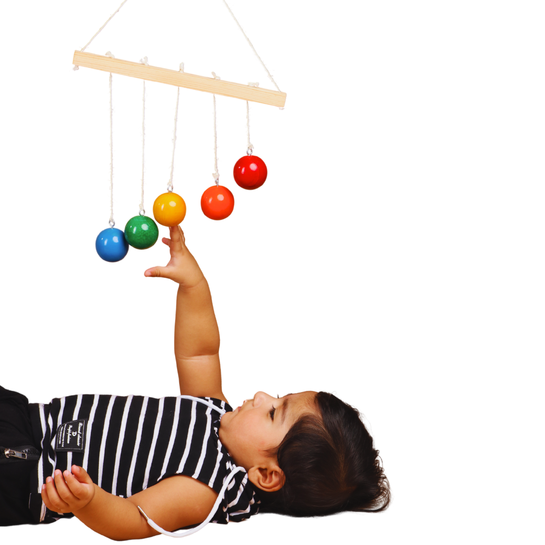 Child playing with a colorful hanging toy on a white background