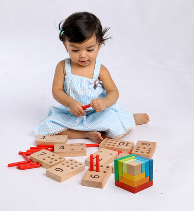 Toddler playing with the BrainyTots Number Pegs Board and Geometric Rainbow Blocks to develop counting skills, fine motor coordination, problem-solving, and spatial reasoning through hands-on Montessori play.