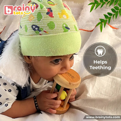 Baby chewing a natural Neem Wood Rolling Drum Rattle to soothe teething discomfort while strengthening grip, sensory exploration, oral development, and fine motor skills through safe Montessori-inspired play.