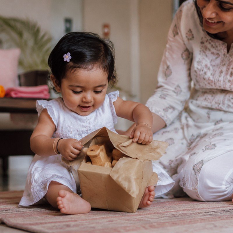 A baby opening a gift wrapped in kraft paper at home