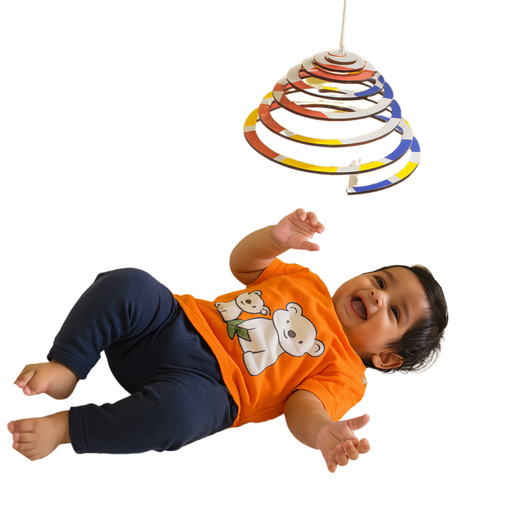 Happy baby reaching toward the BrainyTots Dual-Sided Spiral Hanging Mobile while visually tracking its gentle movement. This Montessori-inspired natural wooden baby mobile encourages visual development, focus, concentration, sensory exploration, and curiosity for newborns and babies aged 0–12 months.