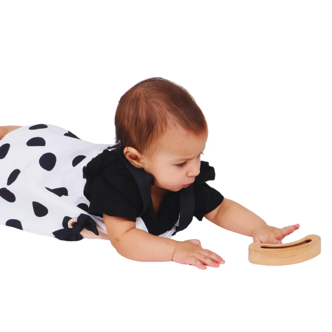 Baby reaching for the BrainyTots Montessori Banana Busy Beads Rattle during tummy time, encouraging grasping, hand-eye coordination, movement, and sensory exploration.