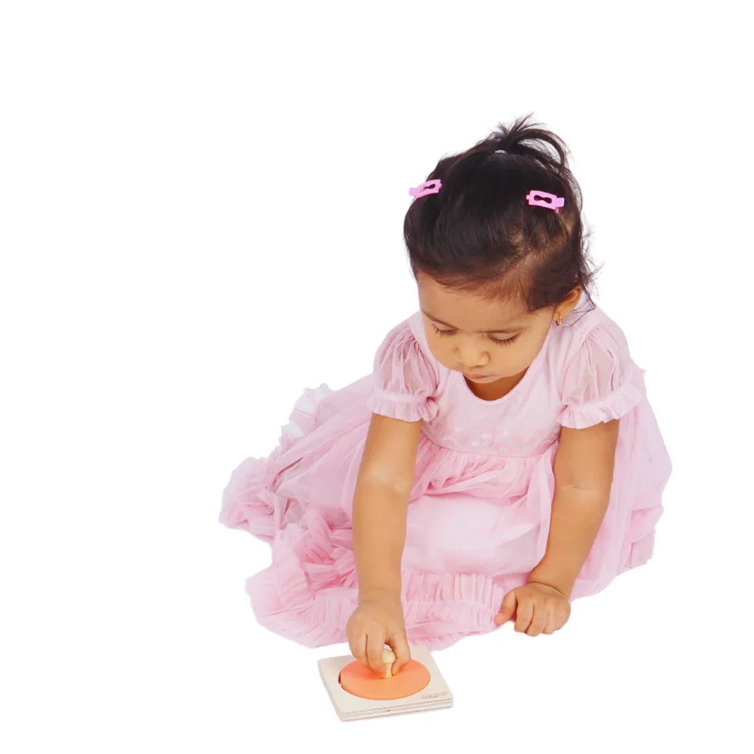 Baby playing with the BrainyTots wooden Circle Shape Puzzle, grasping the knob to practice fine motor skills and hand-eye coordination.