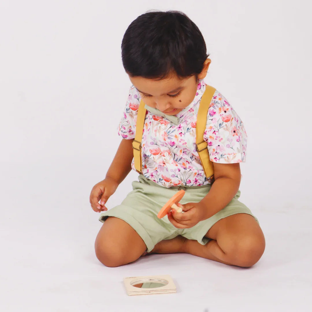 Baby holding the removable piece of the BrainyTots wooden Circle Shape Puzzle while exploring the matching puzzle base during hands-on play.
