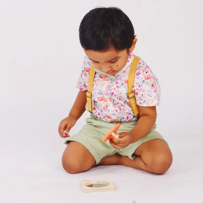 Baby holding the removable piece of the BrainyTots wooden Circle Shape Puzzle while exploring the matching puzzle base during hands-on play.