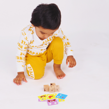 Young toddler arranging wooden emotion cubes while exploring colorful facial expression challenge cards.