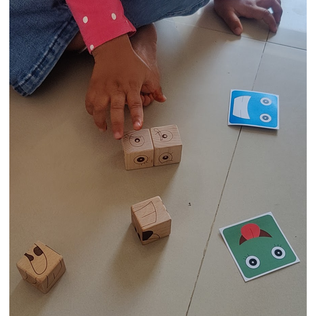 Young boy exploring BrainyTots Face Match Fun Cubes and expression cards during independent play.