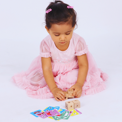 Young girl playing with BrainyTots Face Match Fun Cubes and matching facial expression cards.