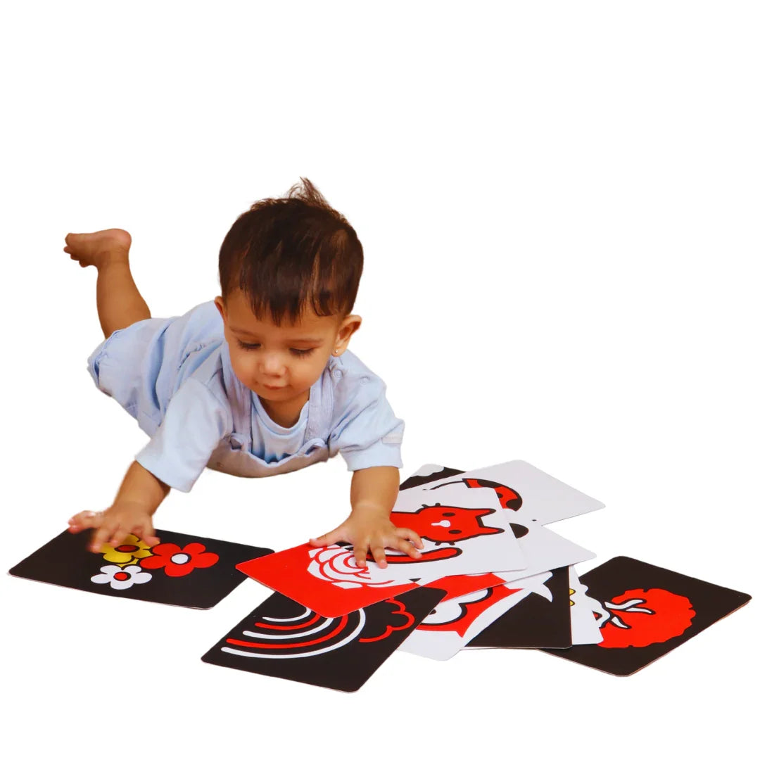 Baby interacting with colorful high contrast flashcards using both hands during hands-on visual play