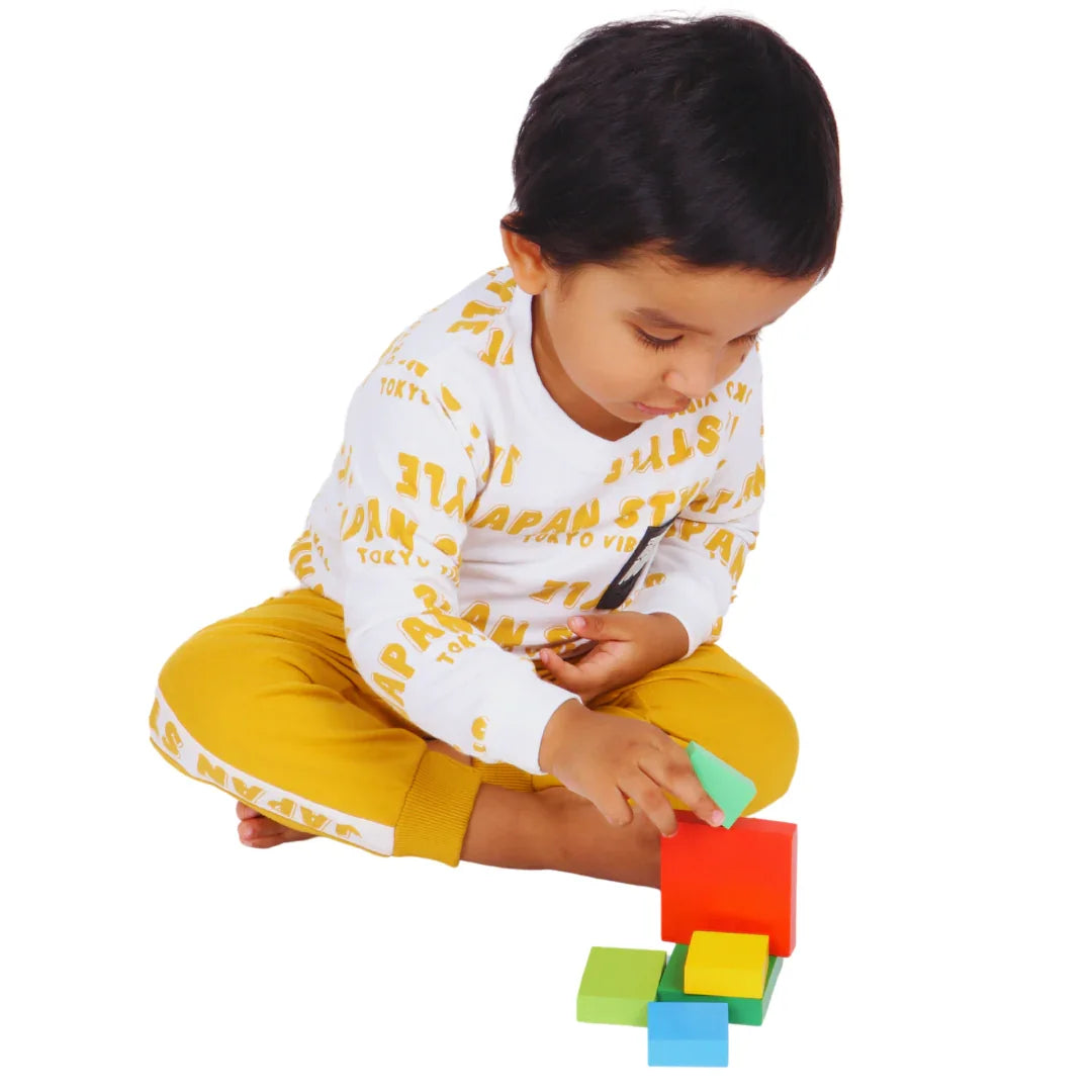 Toddler building a colorful tower with the BrainyTots Montessori Geometric Rainbow Blocks – Shape & Balance Building Set. Designed for children aged 24+ months, this Montessori-inspired wooden toy encourages creative building, spatial awareness, balance, problem-solving, logical thinking, hand-eye coordination, and fine motor skill development through open-ended play.