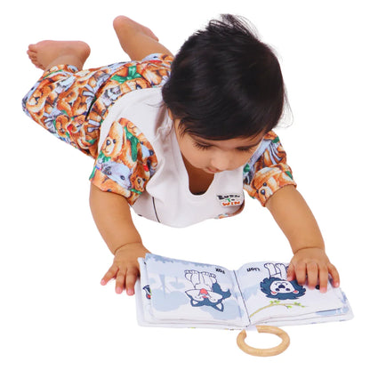 Baby reaching for the BrainyTots Montessori High-Contrast Cloth Book during tummy time, encouraging visual tracking, reaching, hand-eye coordination, sensory exploration, neck strength, and early cognitive development through high-contrast animal illustrations.