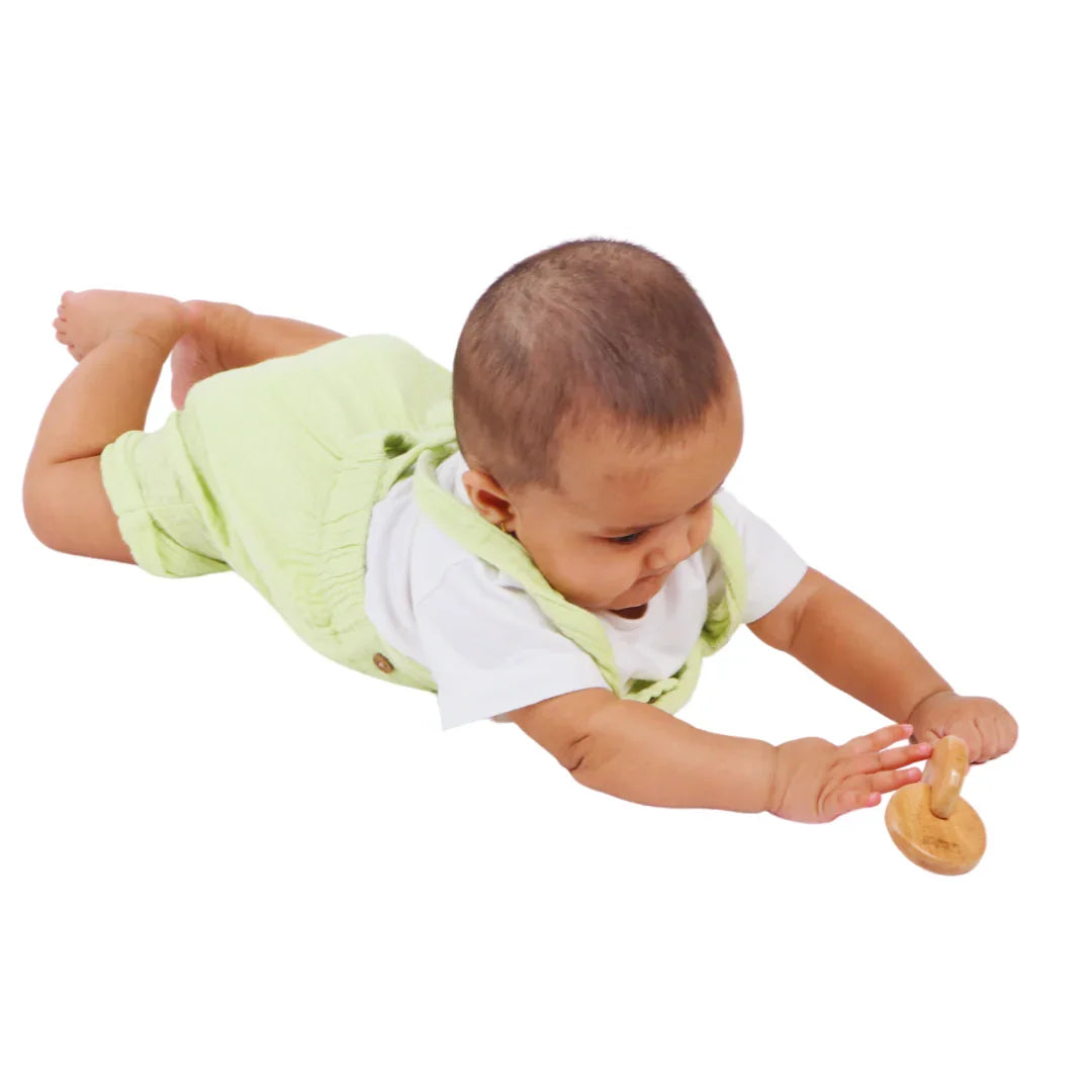 Baby boy reaching toward the BrainyTots Interlocking Discs wooden toy during tummy time play.
