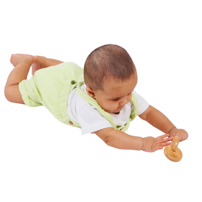 Baby boy reaching toward the BrainyTots Interlocking Discs wooden toy during tummy time play.