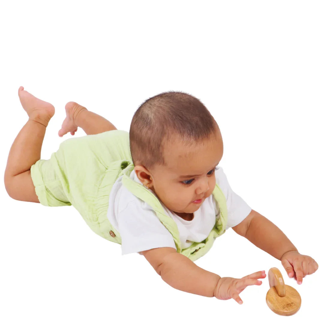 Baby reaching toward the BrainyTots Interlocking Discs toy during tummy time and early motor play.