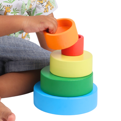 Toddler stacking the BrainyTots Wooden Nesting Bowls, a Montessori-inspired wooden stacking toy that teaches colors, size sequencing, depth perception, hand-eye coordination, fine motor skills, and problem-solving through hands-on play.