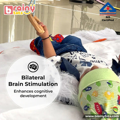 Baby playing with the BrainyTots Neem Wood Teether hanging from a Montessori play gym, supporting bilateral hand coordination, fine motor development, grasping skills, sensory exploration, and independent play during tummy time.