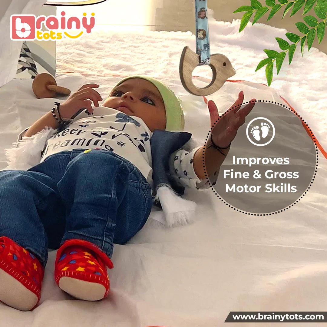 Newborn baby reaching for the BrainyTots Neem Wood Dove Teether from the Montessori Neem Wood Teether Gift Set, encouraging fine and gross motor skills, hand-eye coordination, sensory exploration, and early reaching development.