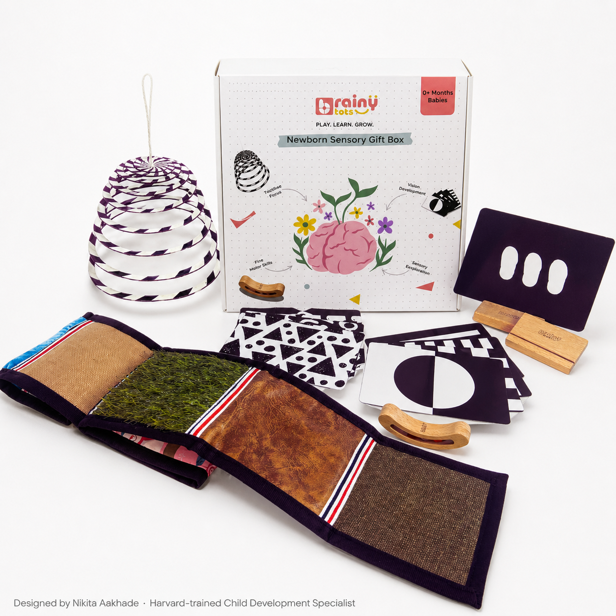 BrainyTots Newborn Sensory Gift Box, a 6-in-1 baby development kit for 0–6 months featuring high-contrast flashcards, sensory texture mat, spiral hanging mobile, busy beads rattle, and flashcard stands for visual, sensory, and motor development.