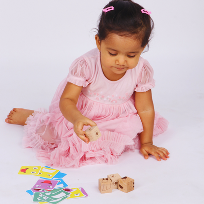 Young boy holding a wooden expression cube while playing with Face Match Fun challenge cards.