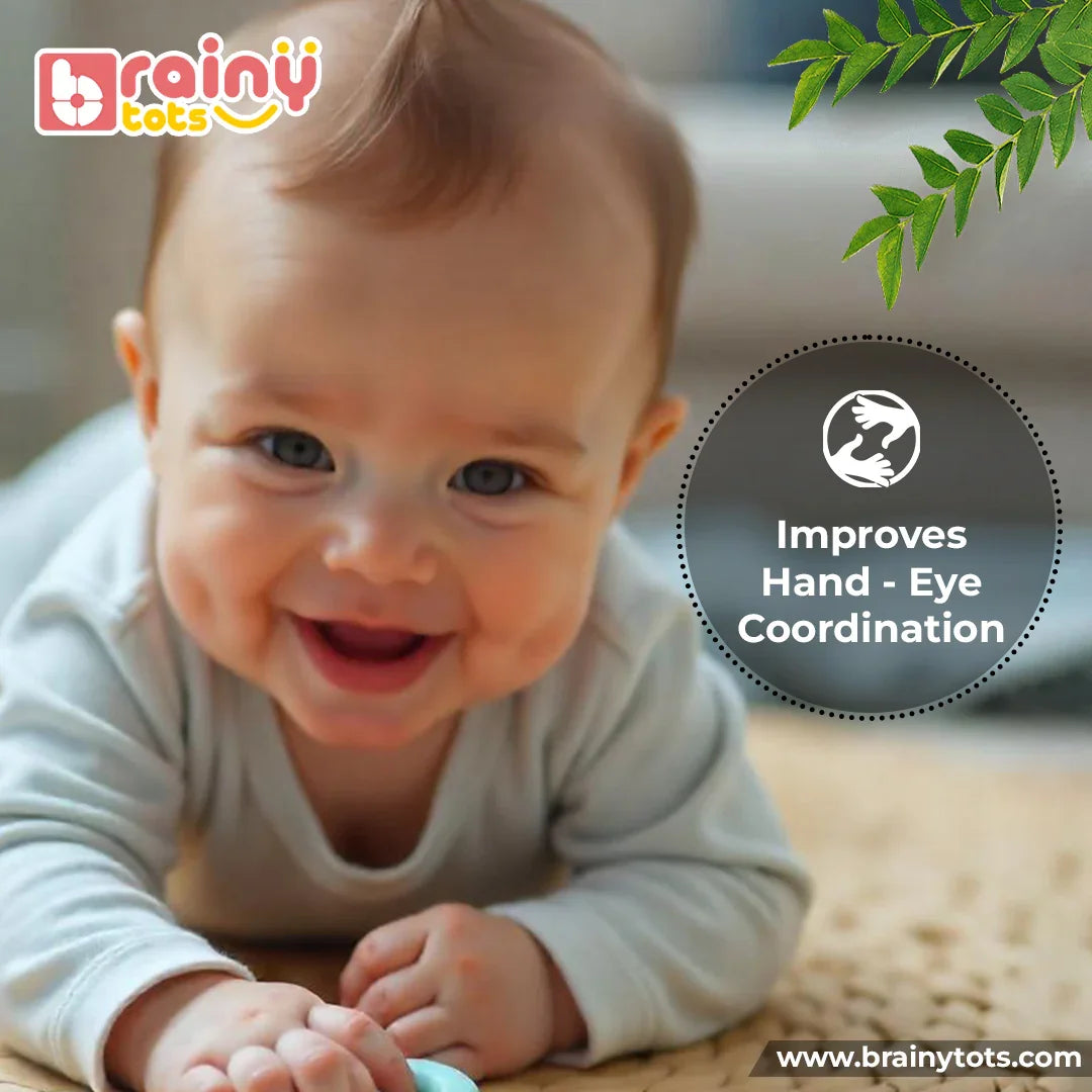 Smiling newborn baby during tummy time using the BrainyTots Montessori Neem Wood Teether Gift Set to develop hand-eye coordination, sensory skills, reaching ability, and early motor development.