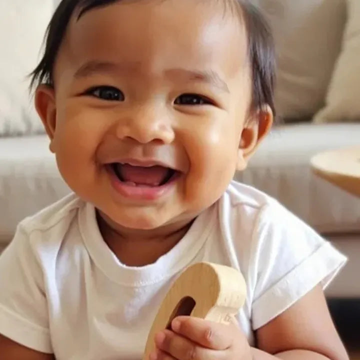 Smiling baby holding the banana busy-beads rattle