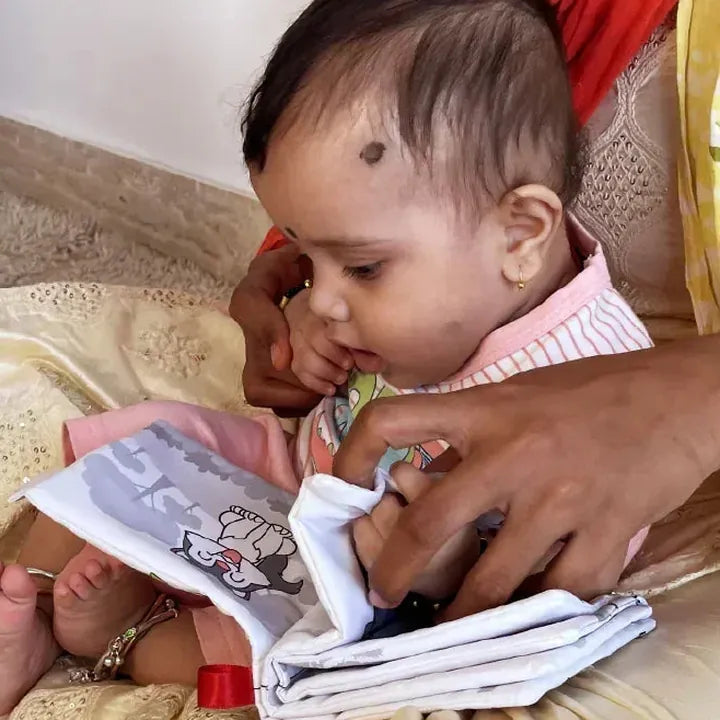 Baby exploring the high-contrast cloth book on a parent’s lap
